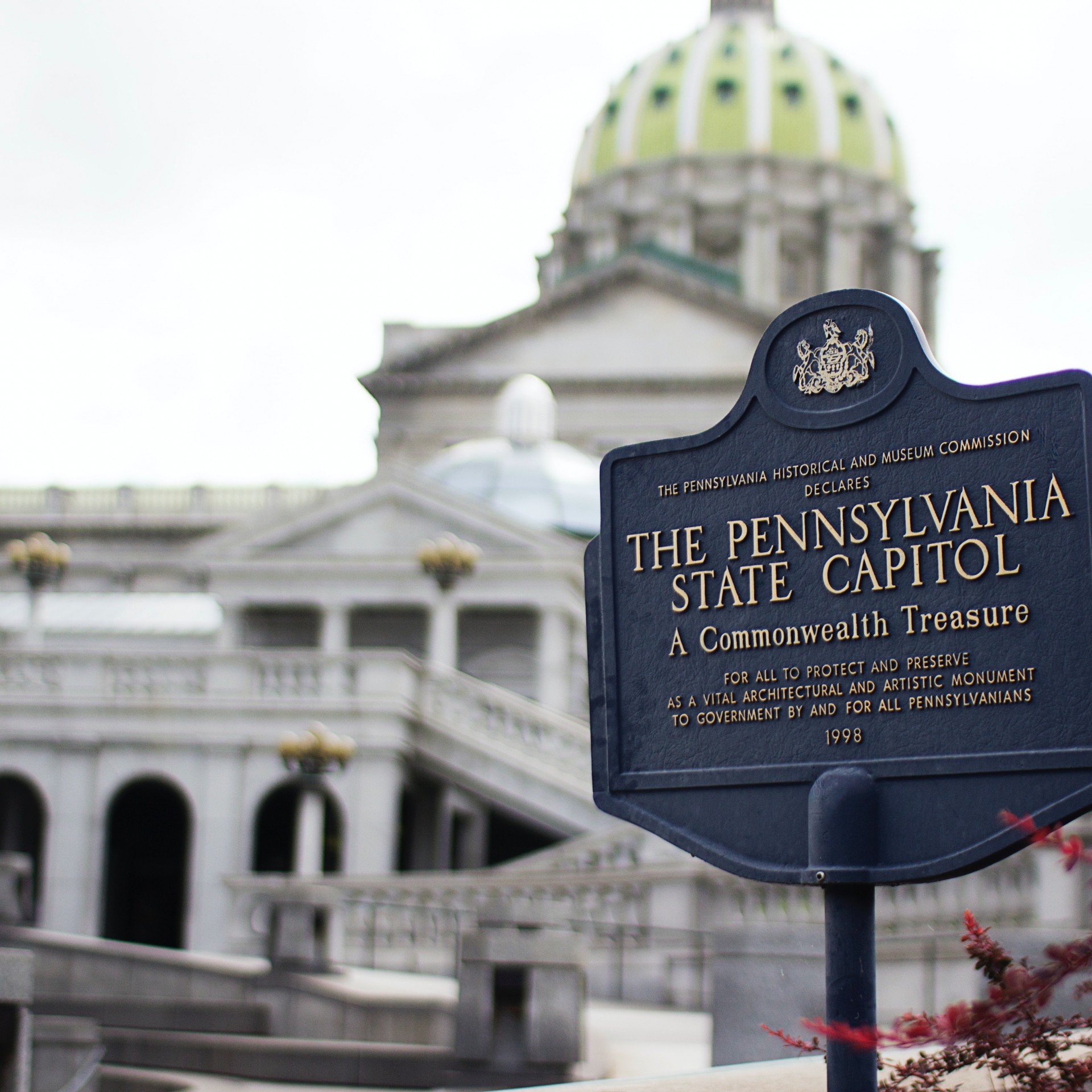 Exterior image of the Pennsylvania State Captial and a sign announing the building in foreground